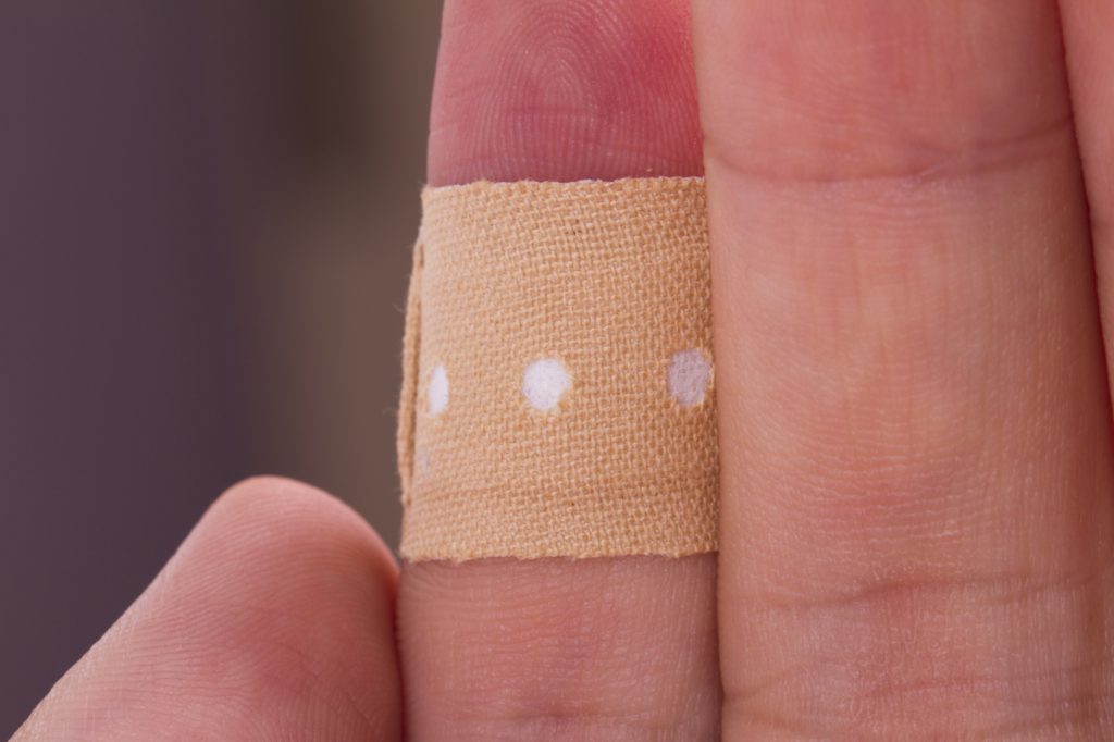 Close up view of adhesive bandage, plaster on index finger, isolated on white background.